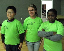 Three children wearing green t-shirts they helped design