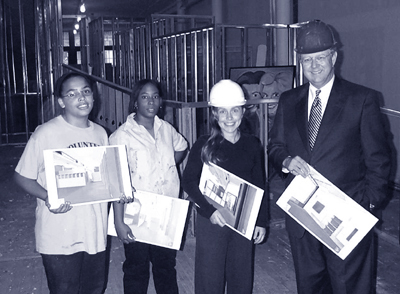 Artists in training, Janae Williams and Stephanie Woodard, Executive Director Jerri Stanard and VP of Public Affairs for Time Warner Cable, Dick Hutchison hold concept drawings of K12 Gallerys new facility.