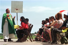 Image of photograph by Gary Harwood titled Bishop Court shows Bishop John Manz celebrating mass on a basketball court near migrant housing.